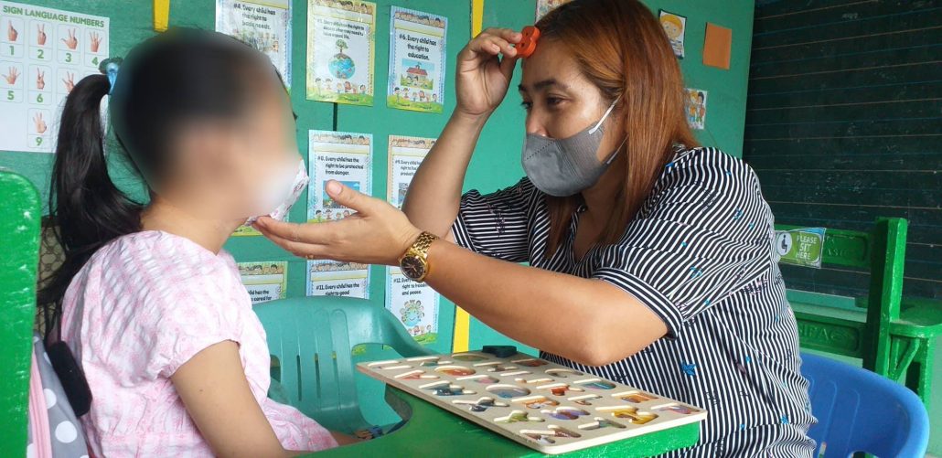 Ma'am Ma. Andrea Gobuyan, teacher at the SPED Center of the New Lucena Central School in New Lucena, Iloilo, teaches the alphabet to a six-year-old kid with special needs.