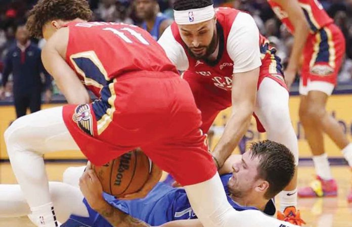 sports-NBA New Orleans Pelicans’ Dyson Daniels (11) and Larry Nance Jr. (in red) gang up on Dallas Mavericks star Luka Doncic (in blue) during a loose ball battle. AP