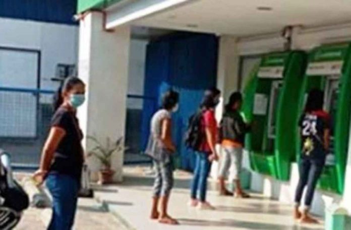 People line up at a Landbank of the Philippines automated teller machine. PNA