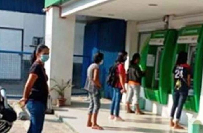 nation1 People line up at a Landbank of the Philippines automated teller machine. PNA