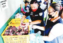 A security guard helps a woman get some red onions from Gabaldon, Nueva Ecija to prevent buyers from getting more than a kilo of the product inside the Agribusiness Development Center at the Department of Agriculture-Kadiwa store in Quezon City. PNA PHOTO BY BEN BRIONES