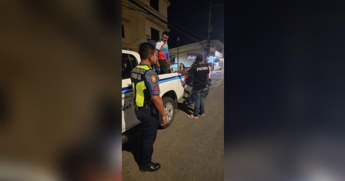 PSTMO pic_superimposed Last night's operation of the Iloilo City Public Safety and Transportation Management Office netted several traffic violators. Photo shows a traffic personnel apprehending a motorcycle driver with two kids as backriders, with no helmet and driver's license. PSTMO PHOTO