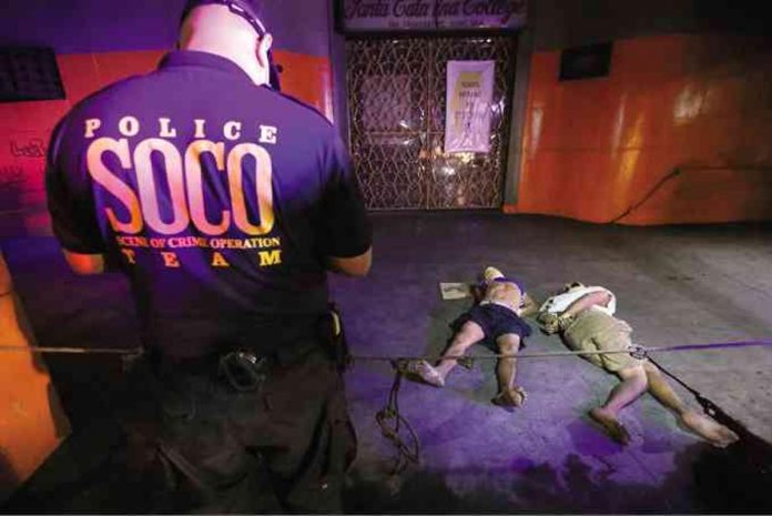 marcos_resized A crime scene investigator of the Metro Manila police inspects the bodies of two men linked to illegal drugs and were found dumped on the streets of the metropolis. FILE PHOTO, INQUIRER/ RAFFY LERMA
