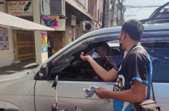 paid parking fees_superimposed A traffic enforcer hands out a flyer about the paid parking ordinance of Iloilo City. The city government starts collecting parking fees from owners of parked vehicles on Monday, May 15. CITY GOV’T OF ILOILO FB PHOTO