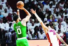 Boston Celtics’ Jason Tatum (left) concentrates on making a shot despite the distraction. AP