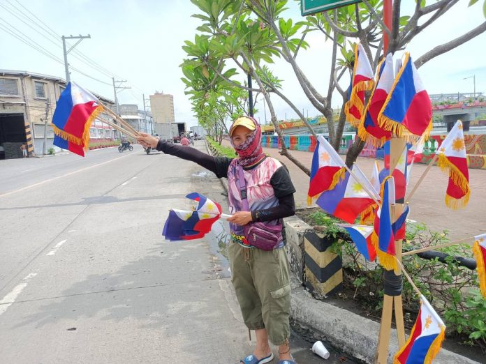 front banner pic and caption A woman sells miniature Philippine flags in Iloilo City. The Philippines celebrates National Flag Day from May 28 to June 12. On these dates, Filipinos are encouraged to display the Philippine flag in all offices, agencies and instruments of government, business establishments, schools, and private homes. AJ PALCULLO/PN