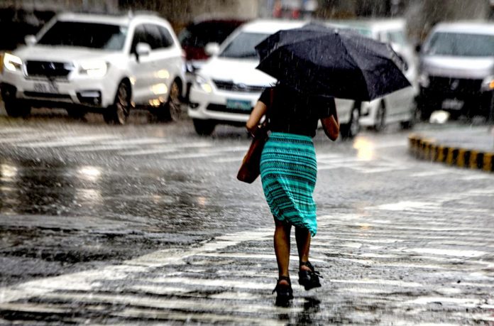 Armed with an umbrella, a pedestrian hurriedly crosses a street under heavy downpour in Kamuning, Quezon City. State weather bureau PAGASA declared the onset of the wet season but the expected El Niño by July or August will bring below-normal rainfall conditions and dry spells in some parts of the country. PNA