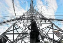 A pedestrian walks past a transmission tower of the National Grid Corp. of the Philippines. INQUIRER FILE PHOTO