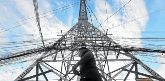 A pedestrian walks past a transmission tower of the National Grid Corp. of the Philippines. INQUIRER FILE PHOTO