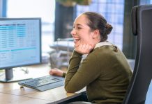 Side view of smiling customer service representative sitting at desk in call centre.