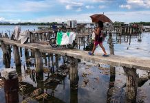 Inflation, COVID plunge 68M into poverty in Asia A woman walks on a narrow bridge towards huts made out of light materials at a fishing community in Bacoor, Cavite on October 30, 2020. GEORGE CALVELO, ABS-CBN NEWS PHOTO