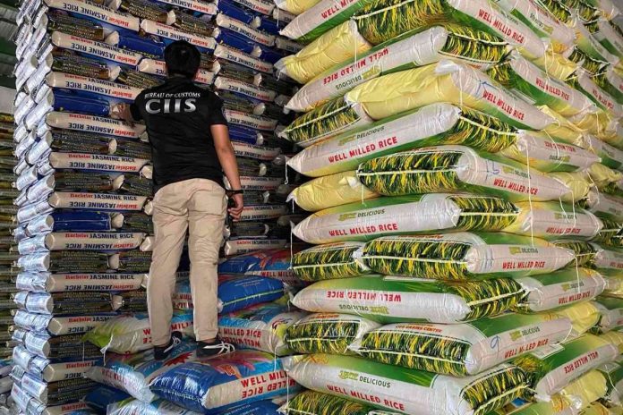 A Customs officer inspects imported rice found in an inspection of three warehouses in Tondo, Manila on Sept. 16. The Bureau of Customs (BOC) on Monday, Sept. 18, said a total of 36,086 sacks of imported rice from Vietnam, Thailand, and Myanmar worth P90.2 million and miscellaneous goods worth P310 million were found during the inspection. BOC PHOTO