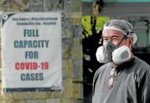 A health worker stands beside an advisory that reads “Full Capacity for COVID-19 cases” posted at a hospital in Pasay City at the height of the pandemic in 2021. File photo by RICHARD A. REYES / Philippine Daily Inquirer