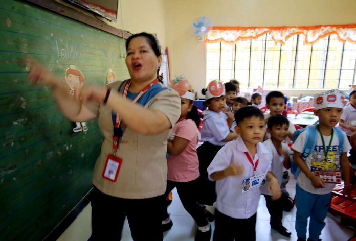 teachers_resized PNA PHOTO. A teacher of President Corazon C. Aquino Elementary School in Quezon City makes the first day of classes a joyful and memorable one for her students on Aug. 29, 2023. She said games should be included in daily lessons to make learning fun.