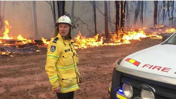 australia_resized Trees burn behind a fire fighter in Asutralia. There are now over 100 fires across the country. BBC