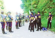 Police gather evidence beside bodies at the scene of a shooting outside a polling station following a confrontation between supporters of rival candidates, during the nationwide village and youth representative elections in Datu Odin Sinsuat town on Mindanao island on Oct. 30, 2023. Photo by Ferdinandh CABRERA / AFP