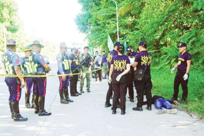 comelec_resized Police gather evidence beside bodies at the scene of a shooting outside a polling station following a confrontation between supporters of rival candidates, during the nationwide village and youth representative elections in Datu Odin Sinsuat town on Mindanao island on Oct. 30, 2023. Photo by Ferdinandh CABRERA / AFP