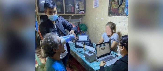A senior citizen of Guimaras has his eyes canned for his national ID. A personnel of the Philippine Statistics Authority is assisting him. PSA-GUIMARAS