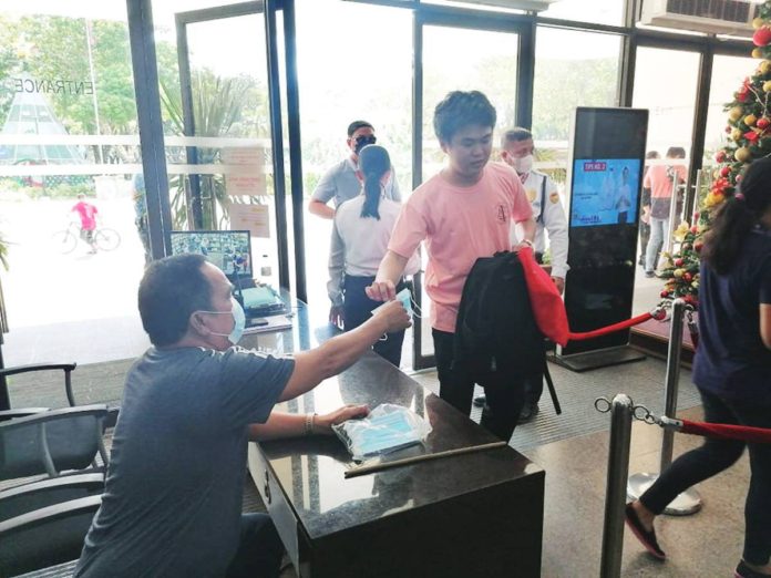 Iloilo City Hall employees and visitors are strongly advised to wear facemasks again. Photo shows a city hall security guard handing out a facemask to a visitor. GLENDA TAYONA PHOTO