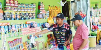 A firecracker vendor attends to a customer at his stall on Circumferential Road 1, Barangay Buhang, Jaro, Iloilo City. This area, one of the city’s three authorized locations for firecracker and pyrotechnic sales, draws a diverse crowd of locals and visitors, all eager to partake in the festive spirit with their purchases. AJ PALCULLO/PN