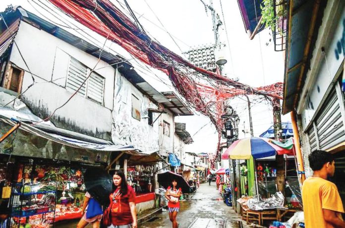 lifeline_subsidy.JPG_resized Electrical cables crisscross one another as electric meters hang on posts in Barangay Old Capitol, Quezon City on July 11, 2023. MARIA TAN/ABS-CBN NEWS PHOTO