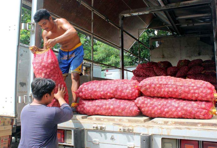 onions_resized Workers unload sacks of onions from the province of Nueva Ecija to be delivered to retail and wholesale stores at Kadiwa market in Cavite. PNA PHOTO BY GIL CALINGA