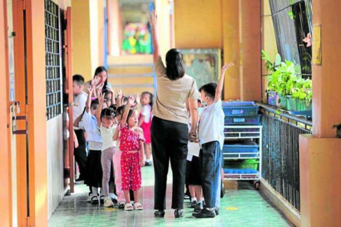 Kindergarten teacher Jill Mary rounds up her pupils during the first day of classes in 2023. FILE PHOTO