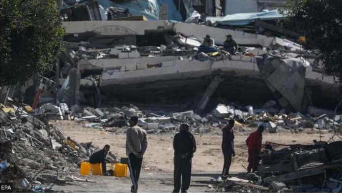 israel.JPG_resized People walk next to destroyed houses in the Gaza Strip. EPA