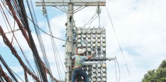 One of the Manila Electric Co. linemen inspects the power meters on a concrete post along Kaliraya Street in Quezon City. PNA PHOTO BY JESS M. ESCAROS JR.