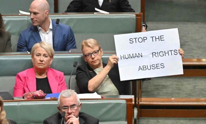 Australian senator Janet Rice, during President Ferdinand “Bongbong” Marcos Jr.’s address to the Australian Parliament on Thursday, pulls up a placard urging the president to “stop the human rights abuses.” PHOTO: JANET RICE ‘X’ ACCOUNT