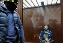 Russian court charges four men with act of terrorism A masked Russian police officer guards a suspect arrested following a terrorist attack at a concert hall in Moscow. BBC