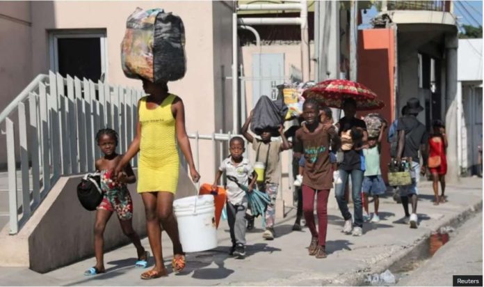 People walk towards a shelter with their belongings fleeing from violence around their homes, in Port-au-Prince, Haiti. REUTERS