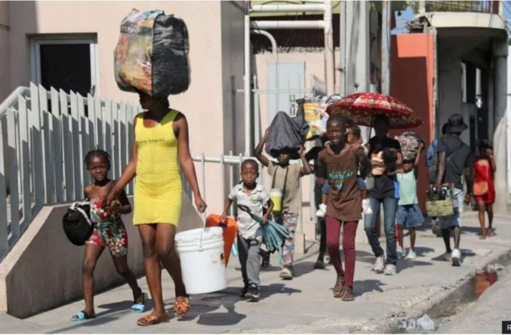 People walk towards a shelter with their belongings fleeing from violence around their homes, in Port-au-Prince, Haiti. REUTERS