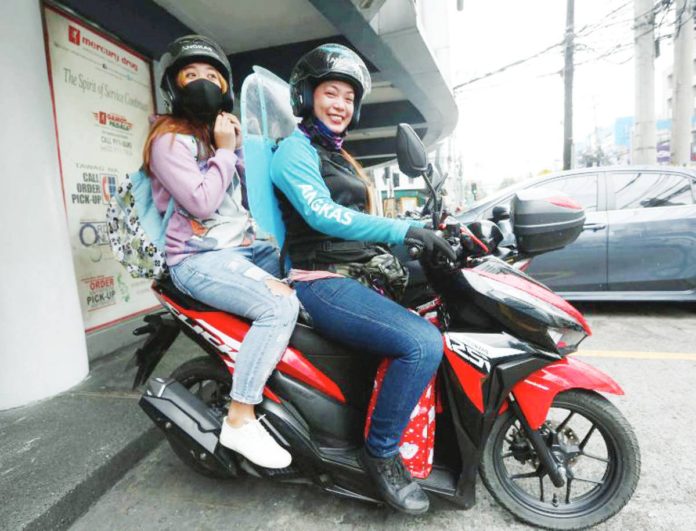 Angkas driver Rizza Capuyan Concha picks up a passenger on Jupiter Street, Makati City. MARIANNE BERMUDEZ/INQMOBILITY.COM PHOTO