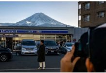 A person stands in front of a shop in Japan, with Mount Fuji in the background. GETTY IMAGES