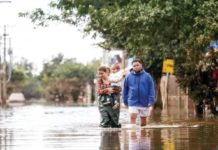 People walk through a flooded street in a flooded Chacara neighborhood in Eldorado do Sul, Rio Grande do Sul state, Brazil. GETTY IMAGES