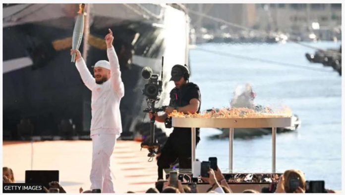 France_resized French rapper Julien Mari aka Jul holds the Olympic Torch after lighting the Olympic and Paralympic torch relays cauldron in Marseille. GETTY IMAGES
