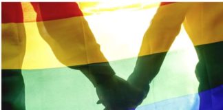 Two people hold hands behind a rainbow flag. In Iran, LGBT people have faced persecution for many years, with rights groups detailing cases of rape, torture and murder. GETTY IMAGES