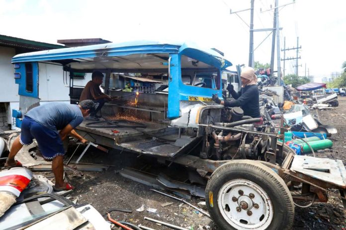 LTFRB_resized Junk shop workers dismantle a public utility jeepney in Tondo, Manila. Operators and drivers who did not consolidate their units with cooperatives under the modernization program will be disenfranchised. PNA