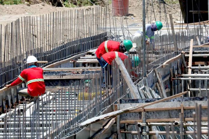 PBBM_resized Construction workers perform their tasks for a road project in Imus, Cavite. They are protected by hard hats and long-sleeved garments but must limit sun exposure between 10 a.m. and 4 p.m. when ultraviolet rays are strongest. President Ferdinand Marcos Jr. has ordered the Regional Tripartite Wages and Productivity Boards to initiate a timely review of the minimum wage rates. PNA