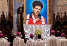 Pope clears way for first millennial to become a saint A tapestry of Carlo Acutis, a teen boy, is seen with people in religious garb looking on during his beatification ceremony in October 2020 in Assisi, Italy. GETTY IMAGES