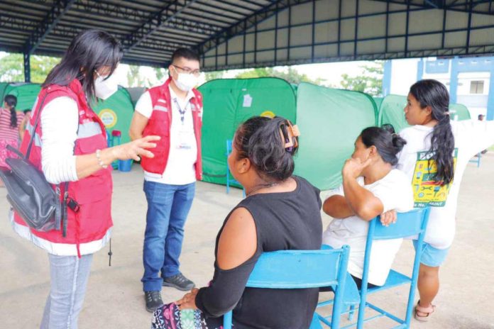 DSWD_pic_resized Arwin O. Razo (standing, 2nd from left), assistant regional director for operations of the Department of Social Welfare and Development Region 6, looks into the situation of evacuees in La Castellana evacuation sites in Negros Occidental. DSWD-6 PHOTO