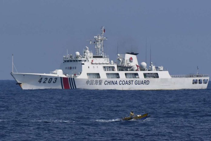 IBP_resized A China Coast Guard ship monitors a Philippine fisherman aboard his wooden boat during the distribution of fuel and food to fishers by the civilian-led mission Atin Ito (This Is Ours) Coalition, in the disputed South China Sea on May 16, 2024. AFP