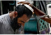 In Karachi, a volunteer sprays water on a bypasser’s face to cool off during a heat wave. GETTY IMAGES