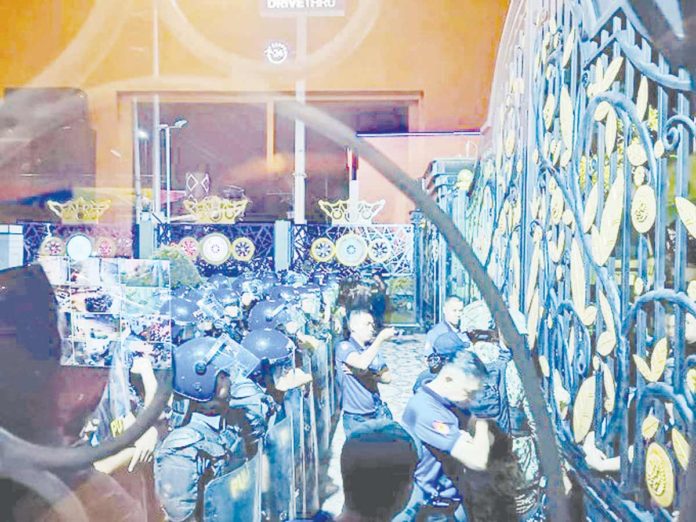 Quiboloy1_resized Policemen in anti-riot gear move in closer to the gate of rthe Kingdom of Jesus Christ compound in Davao City where Pastor Apollo Quiboloy is supposedly hiding. PHOTO FROM X