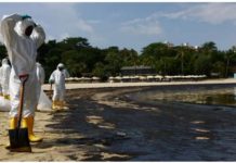 Workers in full body suits clean up the oil spill at the tourist attraction Tanjong Beach. REUTERS
