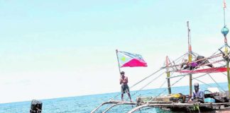 A fisherman waves the Philippine flag near a “payao” or artificial reef close to Panatag (Scarborough) Shoal in the West Philippines Sea to display resistance to Chinese incursions and to show other foreign vessels passing through the area that these waters are part of the country’s exclusive economic zone. FILE PHOTO FROM BIGKIS