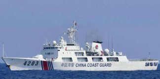 A China Coast Guard ship monitors a Philippine fisherman aboard his wooden boat during the distribution of fuel and food to fishers by the civilian-led mission Atin Ito (This Is Ours) Coalition, in the disputed South China Sea on May 16, 2024. FILE PHOTO/AGENCE FRANCE-PRESSE