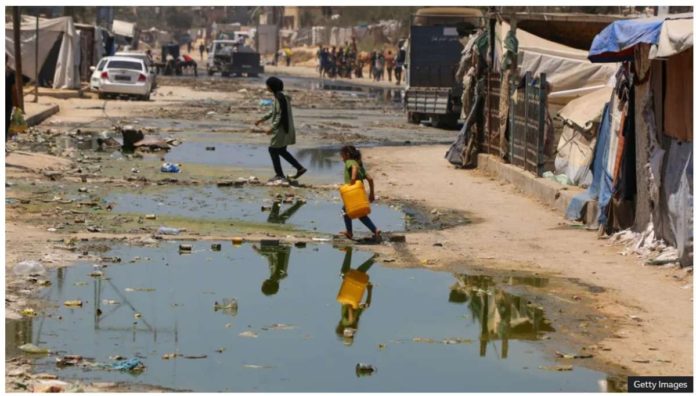 Gaza_resized A child carrying a plastic container to get clean water passes by a street flooded with leaked sewage in the Gaza Strip. GETTY IMAGES