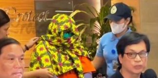 Interior Secretary Benjamin Abalos Jr. (right) presents during a press conference a masked Paulene Canada (center), a co-accused of Kingdom of Jesus Christ founder Pastor Apollo Quiboloy. She was arrested in Davao City.